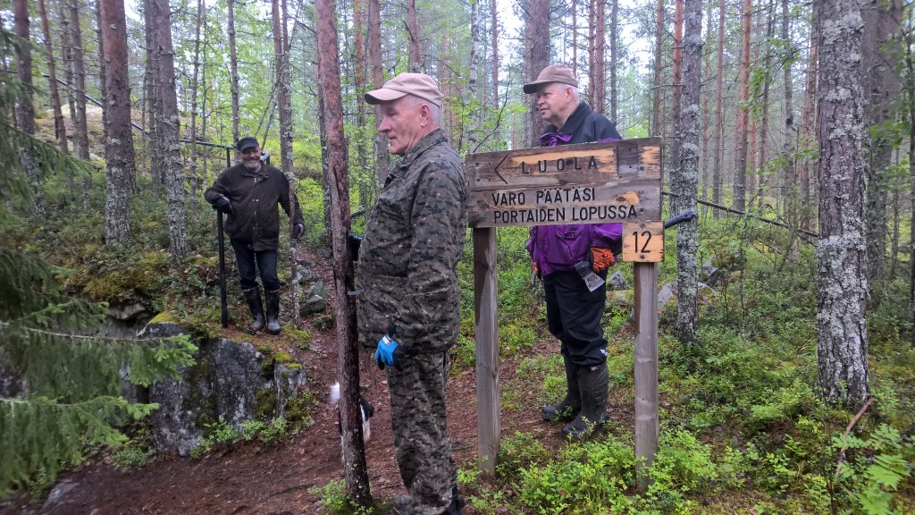 Jongunjoen kyläseuran puheenjohtaja Heikki Turunen, Tauno Oksanen ja Mauri Mönkkönen Vornasenvaaran  huipulla, luolan sisäänkäynnillä.